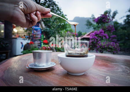 Milchkaffee Tasse morgens Frühstück auf Holztisch mit verschwommenen Berg Hintergrund. Selektive konzentrieren. Frühstück mit einer Tasse Kaffee in der Wunder Stockfoto