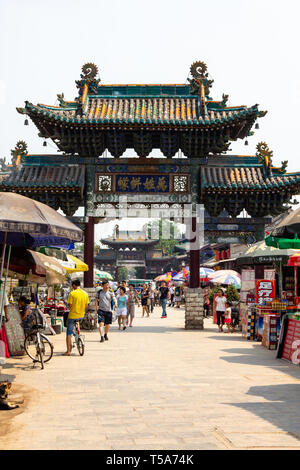 Sep 2013 - Pingyao, Shanxi, China - Touristen unter einem geschnitzten Torbogen Spaziergang in einer der wichtigsten Straßen von Pingyao antike Stadt. Pingyao ist ein Weltkulturerbe der UNESCO Stockfoto