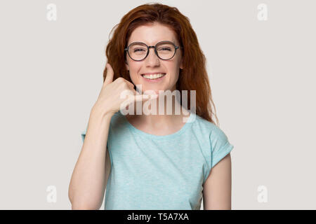 Lächelnd rothaarige Mädchen in Gläser zeigen Anrufen Geste Stockfoto