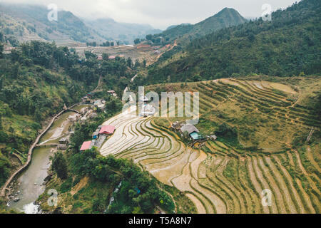 Luftaufnahme von Grünem terrassierten Reisfeldern und Gebäude auf das Tal bei Cat Cat Dorf in Sapa, Vietnam. Stockfoto