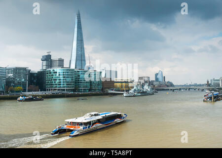 Ein Thames Clipper Schifffahrt auf der Themse mit dem Shard und anderen ikonischen Gebäude im Hintergrund. Stockfoto