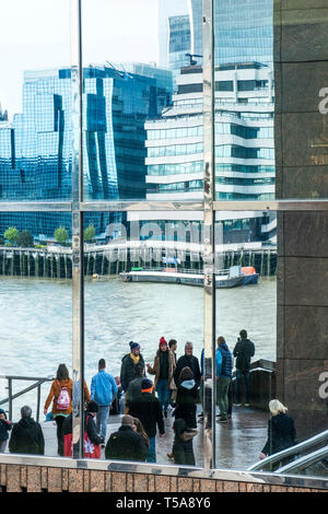 Die verzerrte Widerspiegelung von Menschen und Gebäuden in einem Fenster gesehen. Stockfoto