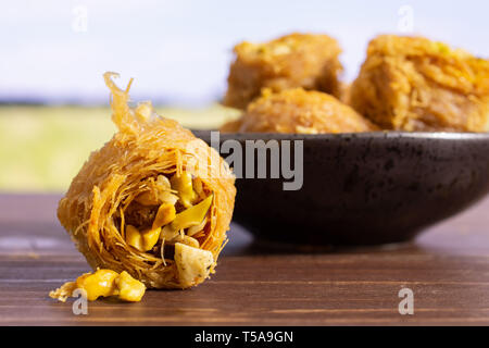 Menge ganz süße Libanesen baklava Stück Vogelnest Vielfalt auf grau Keramikplatte mit grünen Weizenfeld Stockfoto