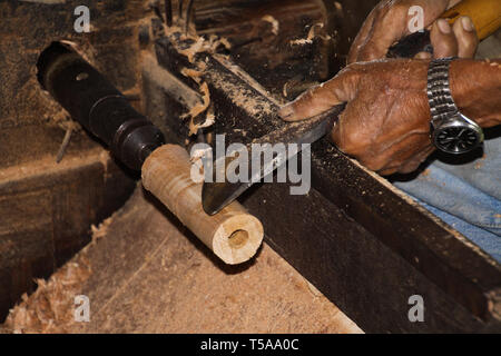 Hände von alten Arbeiter bilden ein Stück Bambus Holz mit Metall Werkzeug in einem Papier Regenschirm Factory in Chiang Mai Stockfoto