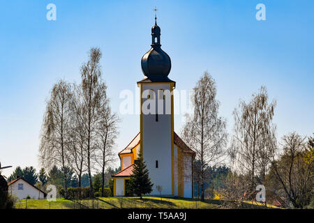 Eine kleine Kirche unter den Bäumen auf dem Hügel. Stockfoto