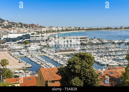 CANNES, Frankreich - April 2019: Blick auf den Yachthafen von Cannes mit der Bucht im Hintergrund. Das große Gebäude beherbergt ein Kasino. Stockfoto