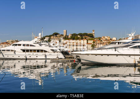 CANNES, Frankreich - April 2019: Superyachten im Hafen von Cannes vor Anker. Im Hintergrund ist das Schloss und der Katholischen Kirche Stockfoto