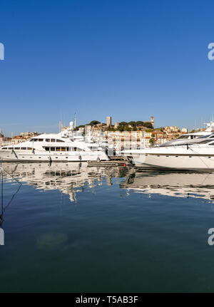 CANNES, Frankreich - April 2019: Superyachten im Hafen von Cannes vor Anker. Im Hintergrund ist das Schloss und der Katholischen Kirche Stockfoto