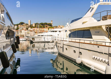 CANNES, Frankreich - April 2019: Superyachten im Hafen von Cannes vor Anker. Im Hintergrund ist das Schloss und der Katholischen Kirche Stockfoto