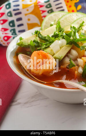 Würzige mexikanische Garnelen Suppe Caldo de Camaron mit Avocado gewürfelte Zwiebeln, Koriander und Limettensaft Keil garnieren Stockfoto