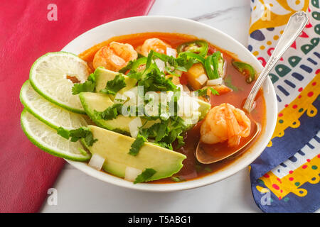 Würzige mexikanische Garnelen Suppe Caldo de Camaron mit Avocado gewürfelte Zwiebeln, Koriander und Limettensaft Keil garnieren Stockfoto