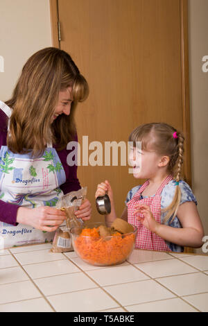 Mutter und Tochter lachend während brauner Zucker in die Schüssel giessen, während Sie karottenkuchen. (MR) Stockfoto