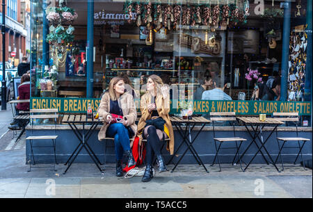 Zwei junge Frauen sitzen und Reden, außerhalb eines Café Restaurant, Soho, London, England, UK. Stockfoto