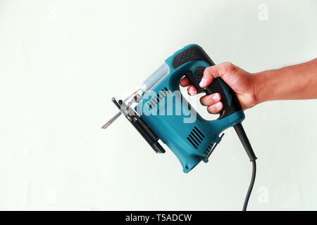 Hand hält eine elektrische Säge auf weißem Hintergrund Stockfoto