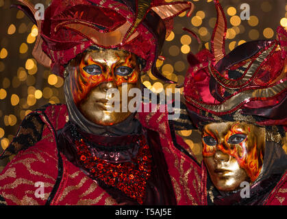 Karneval in Venedig paar Feuer rot tragen Masken und Kostüme, Italien, Nachtporträt mit bokeh Lichter Hintergrund Stockfoto