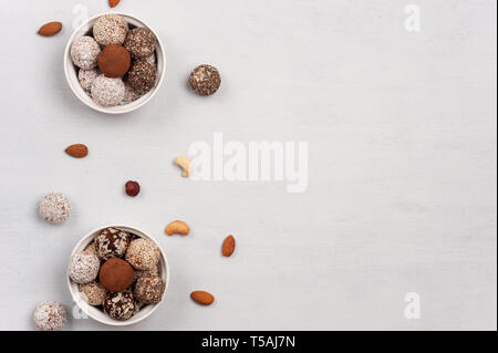 Andere Energie Kugeln in der Keramik licht Schalen und Muttern auf einer Fläche verstreut. Leckereien sind lecker, süß, keine Backen, Glutenfrei. Stockfoto