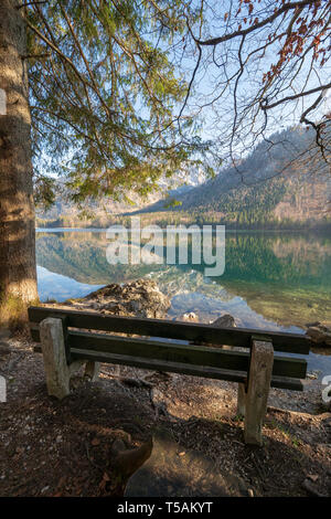 Leere Holzbank am Ufer des vorderen Langbathsee in der Nähe von Ebensee, OÖ, Österreich, mit der großartigen Landschaft auf dem kristallklaren Wasser widerspiegeln Stockfoto