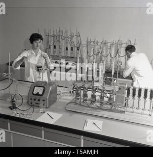 1960, historische, männliche und weibliche Forscher in weißen Kitteln, die Durchführung von Experimenten im Labor, England. UK. Sie forschen und arbeiten im Bereich der Pflanzen- und Gartenbau. Stockfoto