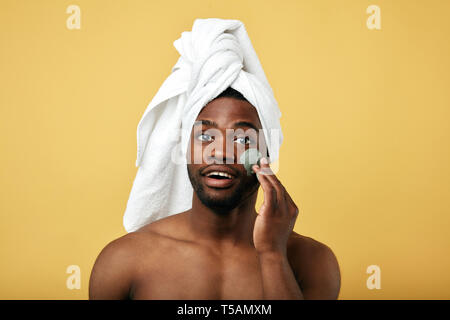 Junge glücklicher Mann mit einem Handtuch auf dem Kopf, die Maske auf dem Gesicht, Nahaufnahme Foto, Tagesablauf Konzept. Gesundheitswesen Stockfoto