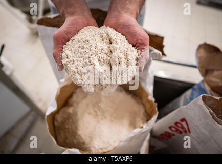 17. April 2019, Hessen, Steinau an der Straße: In seinem Bäcker, bäckermeister Jürgen Fink steht von einem Sack von organischen Dinkelmehl, die er in seinem Brot neben andere regionale Produkte verwendet. Unter dem Motto "Backen mit Liebe und Zeit', die Firma, die Familie seit vielen Generationen im Familienbesitz, arbeitet nach alten handwerklichen Traditionen ohne industrielle Backmischungen oder tiefgekühlte Teige. Foto: Frank Rumpenhorst/dpa Stockfoto