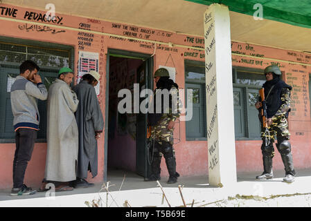 Anantnag, Jammu und Kaschmir, Indien. 23 Apr, 2019. Die regierungstruppen gesehen stehen auf der Hut wie Kaschmir Wähler in einer Warteschlange stehen, ihre Stimmen vor einem Wahllokal in Anantnag, in Kaschmir zu werfen. In der dritten Phase der Parlamentswahlen in Indien Wahlen, Inder, die auf Umfragen unter komplett heruntergefahren und Internet gag ging. Kredit Idrees: Abbas/SOPA Images/ZUMA Draht/Alamy leben Nachrichten Stockfoto