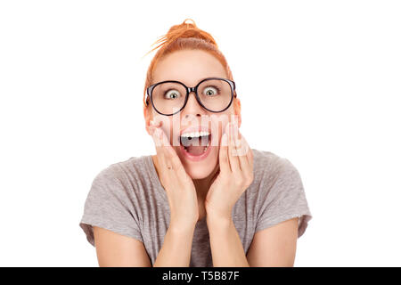 Closeup Portrait von verwirrten Frau mit Ingwer Haar Brötchen in Brillen halten die Hände auf die Wangen, mit großer Schock Überraschung, Verblüffung in der Kamera Stockfoto
