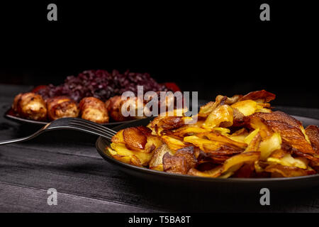 Bratkartoffeln und hausgemachte gegrillte Würstchen oder chevapchichi mit gedünstetem Rotkohl sauer auf Holz rustikale Hintergrund. Ansicht von oben. Stockfoto