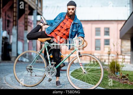 Portrait eines bärtigen Mann wie ein Verrückter hipster Spaß mit retro Fahrrad draußen auf der industriellen städtischen Hintergrund Stockfoto