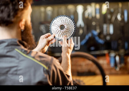 Handwerker Holding hinteren Zahnrad stars vor der Installation mit dem Mountainbike in der Werkstatt Stockfoto