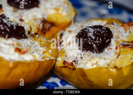 Äpfel gebacken mit Hüttenkäse und mit Schokolade dekoriert und Kokosnuss ein Chips. Stockfoto