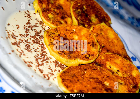 Käsekuchen mit saurer Sahne und Schokolade Chips auf einer Platte. Stockfoto