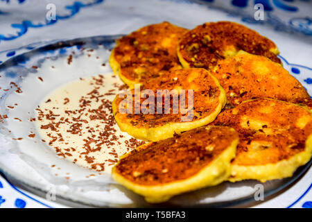 Käsekuchen mit saurer Sahne und Schokolade Chips auf einer Platte. Stockfoto