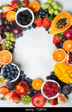 Rahmen aus gesunden rohen Früchten, Mango papaya Erdbeeren Passionsfrüchte orangen Beeren auf ovalen Servierteller auf Licht konkreten Hintergrund, Ansicht von oben, Kopieren, selektiven Fokus Stockfoto