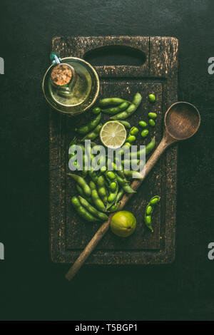 Grüne Edamame Sojabohnen auf Holz Schneidebrett mit Kochlöffel, Ansicht von oben. Gesunde vegetarische Kost Stockfoto