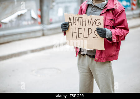 Porträt eines obdachlosen Bettler auf der Straße mit sozialen Botschaft auf die Pappe. Close-up auf eine Nachricht Stockfoto