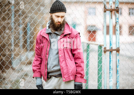 Porträt einer gedrückten obdachlosen Bettler oder Gefangenen stehen in der Nähe der alten Metall Zaun im Freien Stockfoto