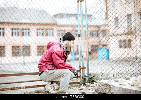 Porträt einer gedrückten obdachlosen Bettler oder Gefangenen stehen in der Nähe der alten Metall Zaun im Freien Stockfoto