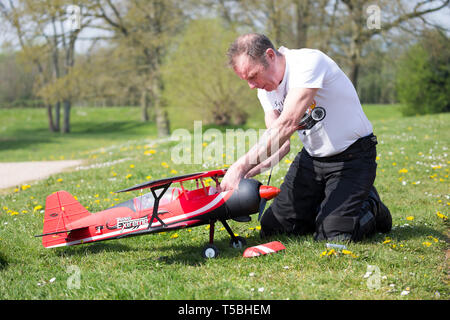 Nahaufnahme von Mann in Country Park (der Controller) kniend auf Gras, zur Festsetzung der Empfänger/Anpassungen an seinen Funkgesteuerten, flugmodell Flugzeug. Stockfoto
