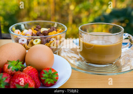 Heißer Kaffee, cornflekes, Kochen Eier und reife Erdbeeren zum Frühstück Stockfoto