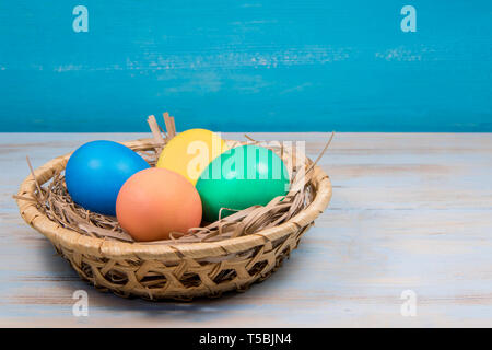 Warenkorb bemalte Ostereier in verschiedenen Farben auf blauem Hintergrund mit einem Platz für die Inschrift Ostern Konzept Stockfoto