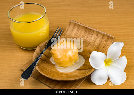 Aclair gekrönt mit süße Kondensmilch in Holzplatte mit einem Glas Leidenschaft Fruchtsaft auf hölzernen Tisch Stockfoto