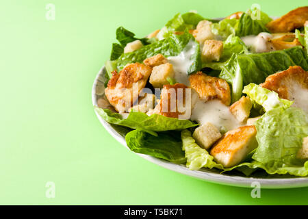 Caesar Salat mit dem Salat, Hühnchen und Croutons auf grünem Hintergrund. Stockfoto