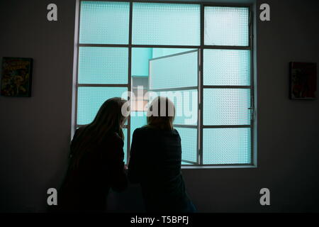 Silhouette von Frauen und Mädchen heraus suchen Fenster aus Milchglas, Türkis Fenster. Stockfoto