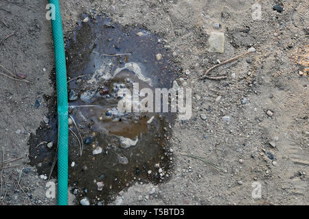 Eindringen von Wasser aus dem Loch in einem Schlauch Stockfoto