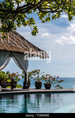 Indonesische Ballen mit Betten und Blumentöpfe mit Infinity Pool auf der Klippe mit Blick auf den Ozean. Lifestyle, Entspannung, tropische Ferien. Stockfoto