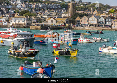 Morgen Flut mit Fischerbooten auf ihren Liegeplatz im Hafen von St. Ives St. Ives, Cornwall UK Europa mit blauer Himmel & Kirche & Gebäude in backgroun Stockfoto