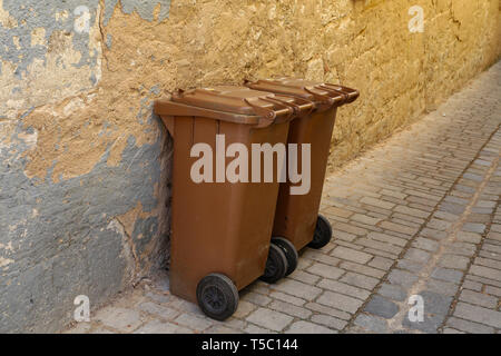 Braune Mülltonnen vor einer Mauer eines Hauses Stockfoto