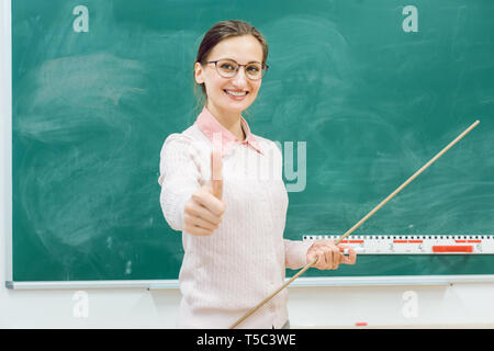 Freundliche Lehrerin stand vor der Tafel in der Klasse Stockfoto