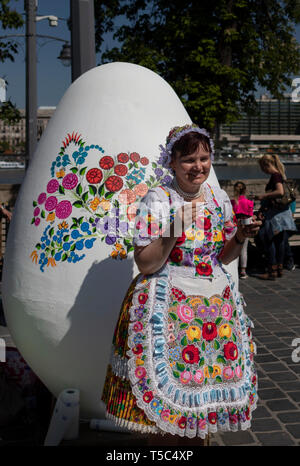 BUDAPEST/UNGARN - 04.21.2019: eine Frau, die Traditionelle bestickte Tracht ziert ein riesiges Osterei mit floralen Mustern. Stockfoto