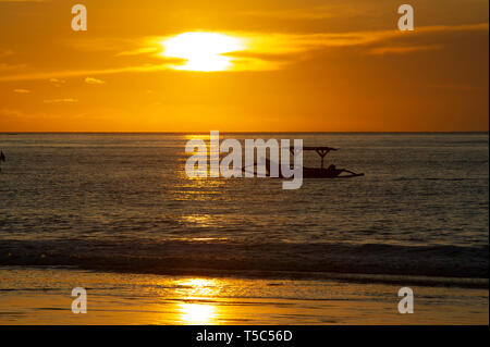 Ein traditionelles balinesisches Fischerboot Jukung bei Sonnenuntergang am Strand Jimbaran, Bali, Indonesien Stockfoto